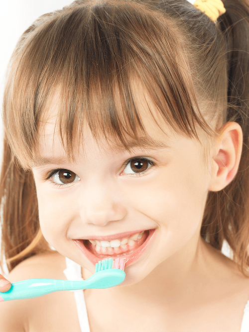 Little girl smiling and holding a toothbrush